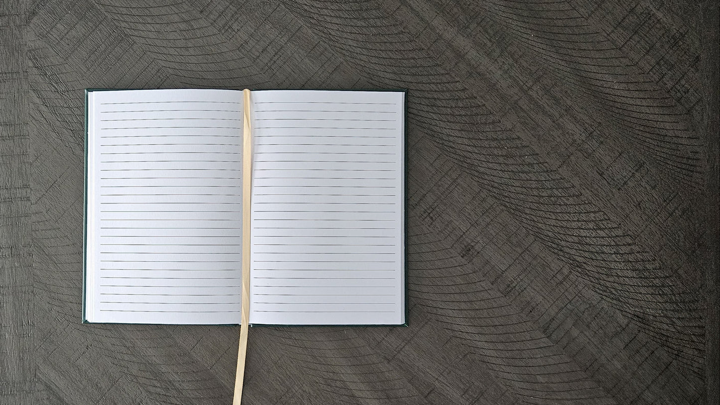 Open notebook with a wooden stick on a textured dark surface