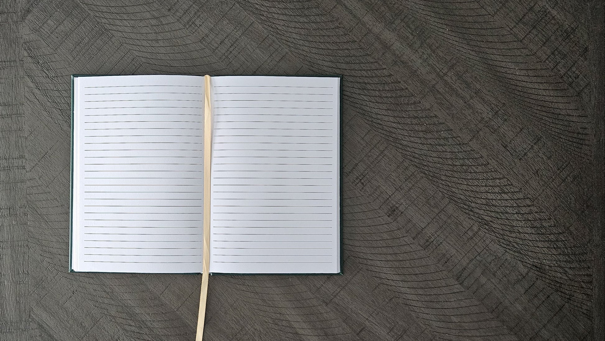 Open notebook with a wooden stick on a textured dark surface